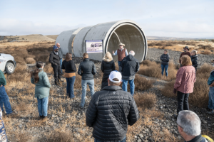 A group of people gathered around a large pipeline