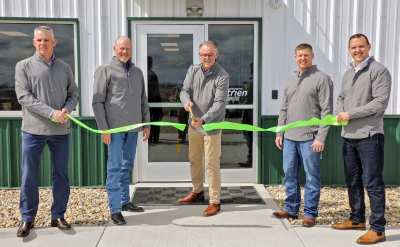 Five men cut a green ribbon in front of a building