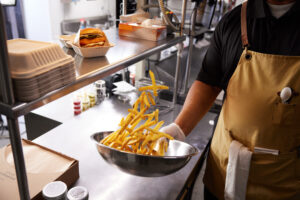 Crisp french fries are tossed in a pan by a chef