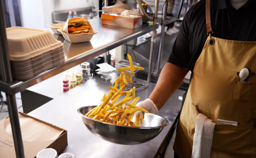 Crisp french fries are tossed in a pan by a chef