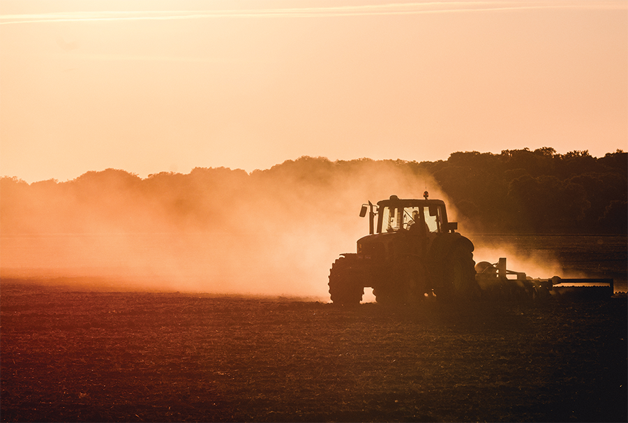 A tractor silhouetted against a sepia sky