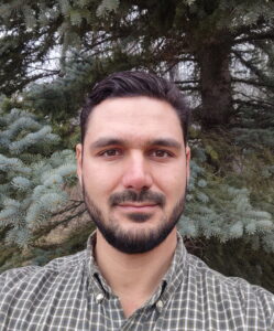 Headshot of a man with dark hair and a dark beard