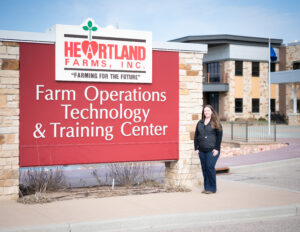 A woman stands by a large sign