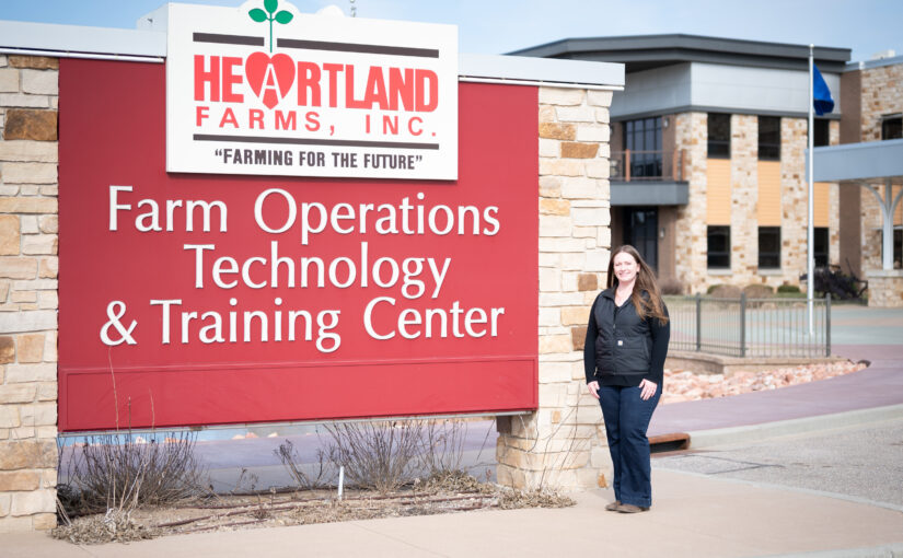 A woman stands by a large sign