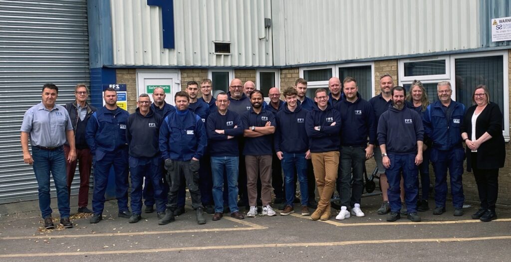 A group of employees pose in front of a building