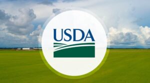 The USDA logo against a background of a blue sky and a green field