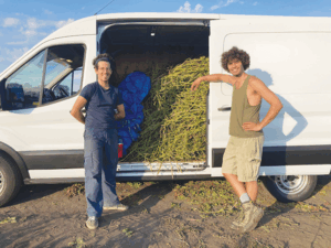 Two men pose beside a van containing potato plant waste that will be turned into fiber.