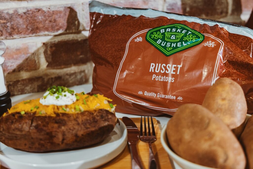 A package of potatoes next to a freshly baked spud