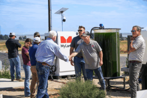 Men shake hands with MyLand equipment in the background.