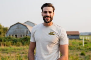A bearded young man smiling in a potato field