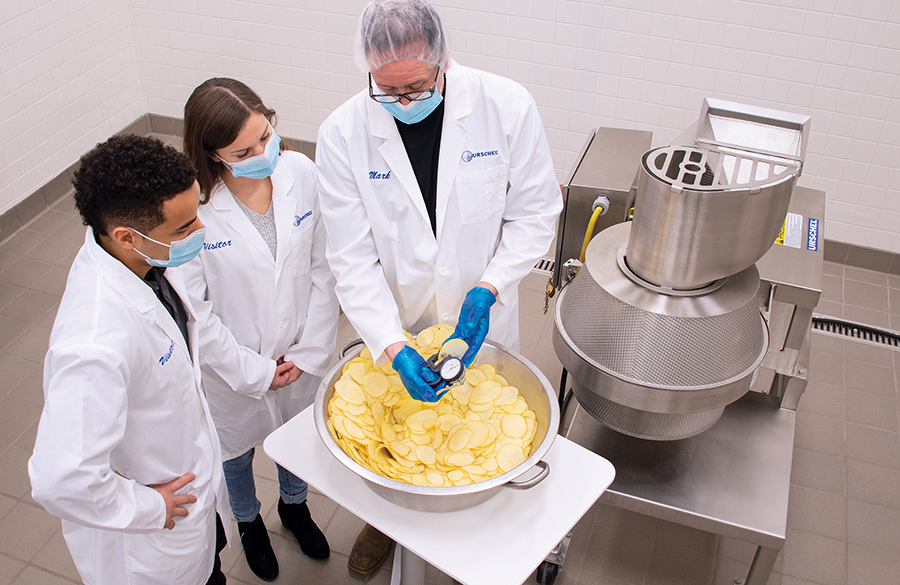 Lab researchers gather around chip processing equipment