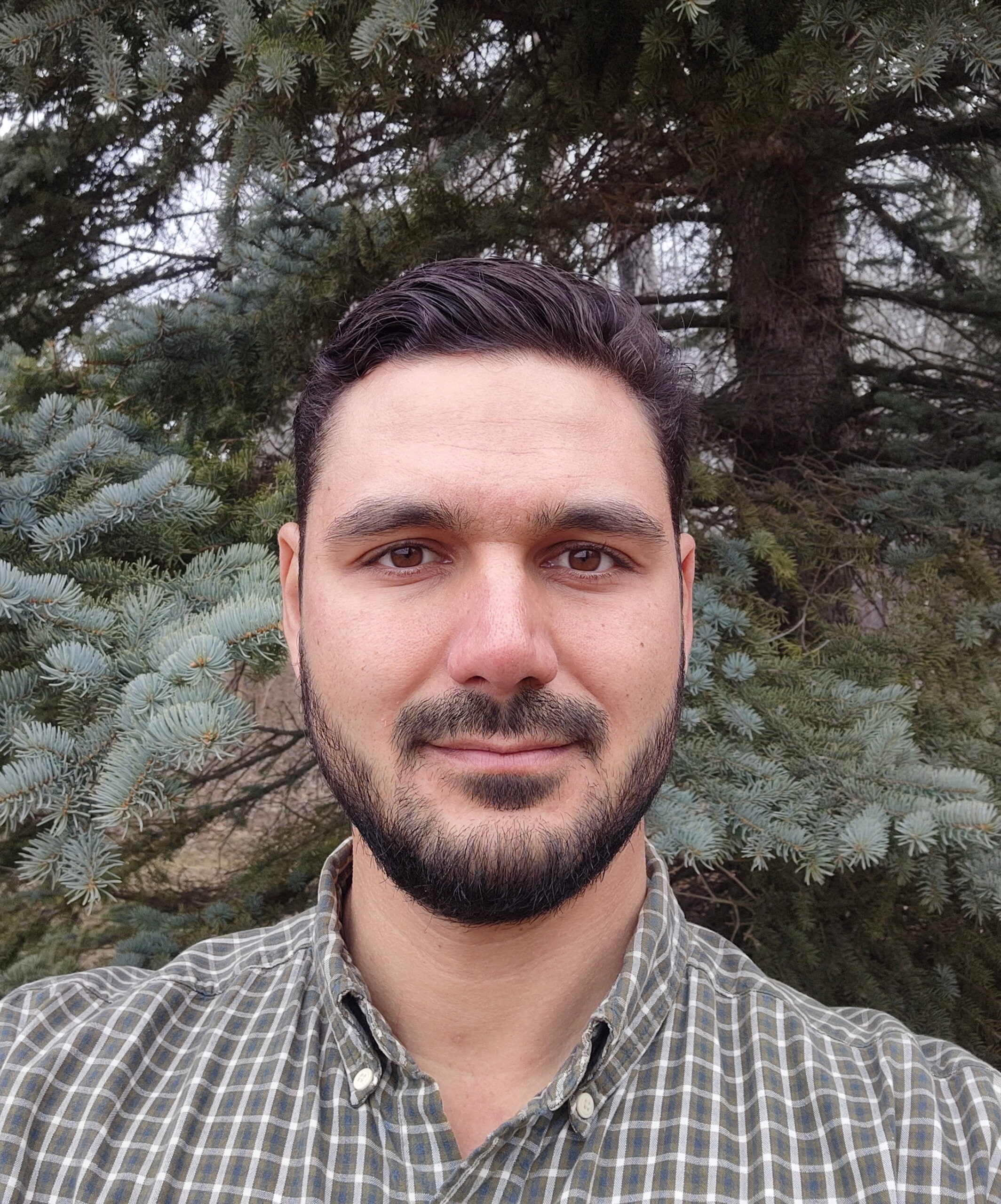 Headshot of a man with dark hair and a dark beard