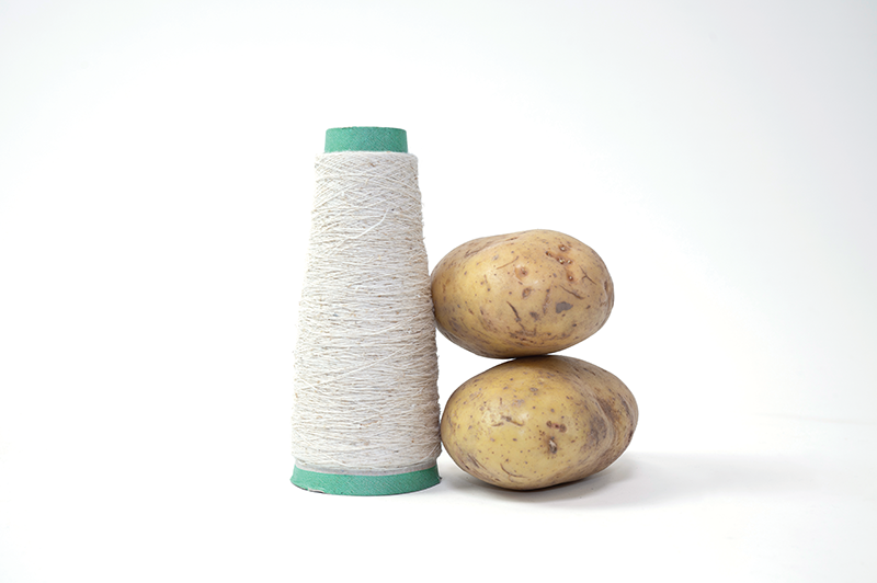 An image featuring two potatoes stacked next to a spool of white thread