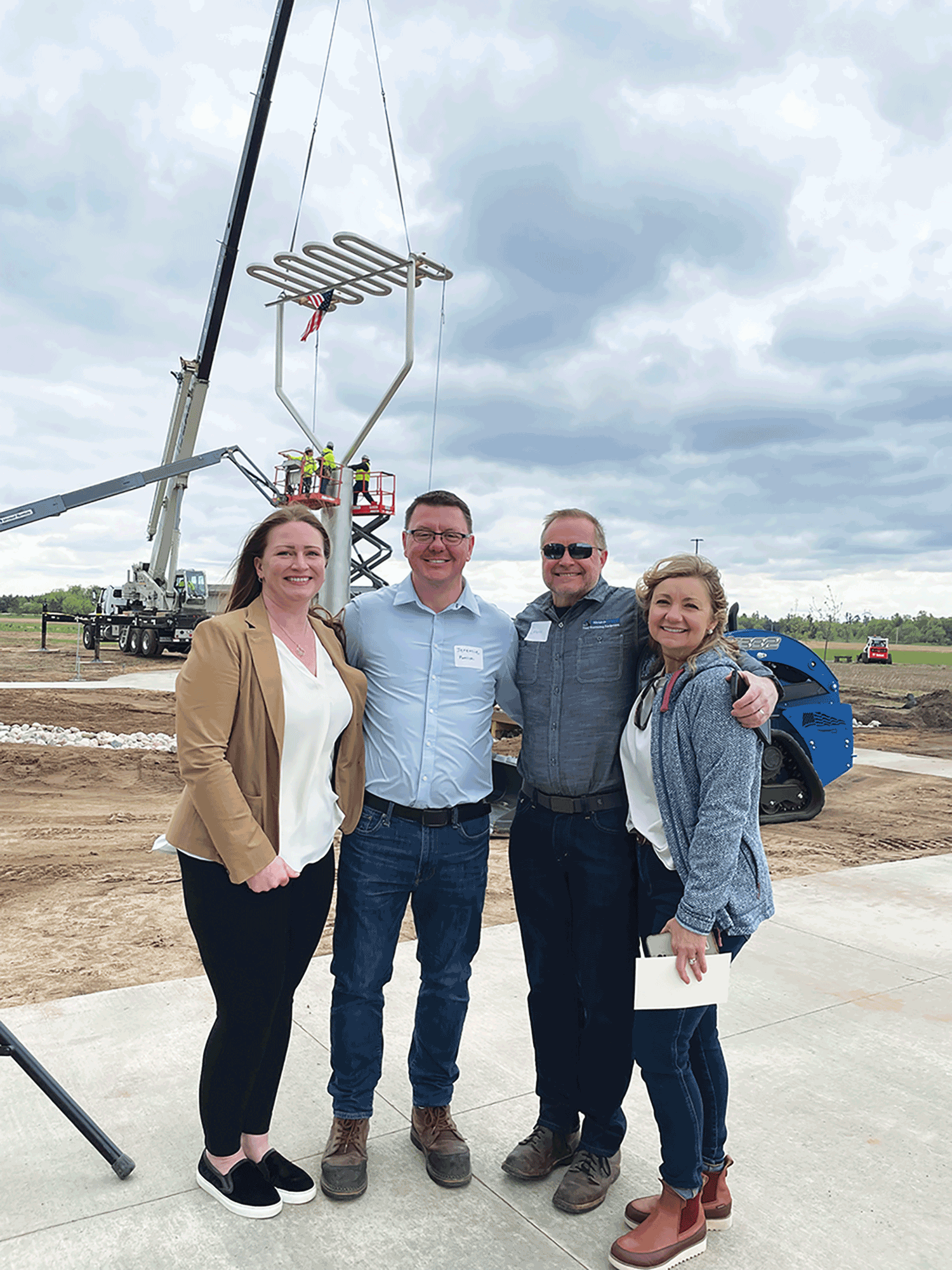 People pose in front of a 39-foot potato masher sculpture at Heartland Farms