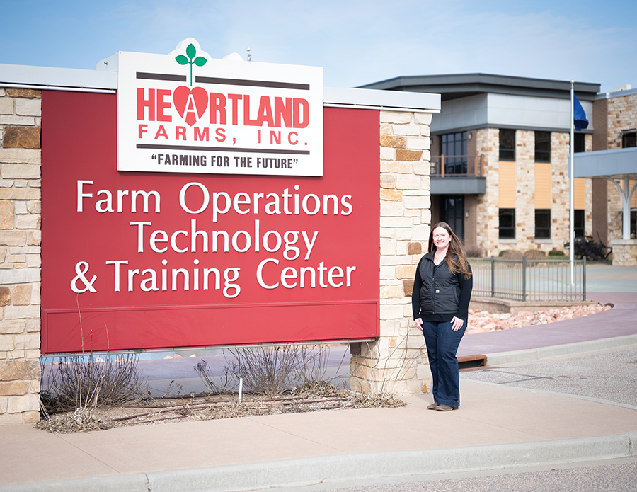 A woman poses in front of large red-and-white sign