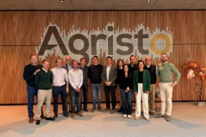 A group of people pose in front of the Agristo company logo.