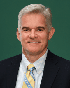 Headshot of man in dark jacket and yellow tie