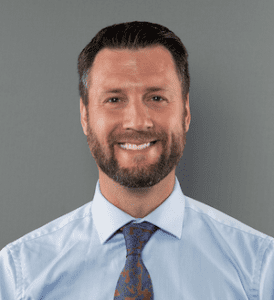 Headshot of a smiling man in a shirt and tie